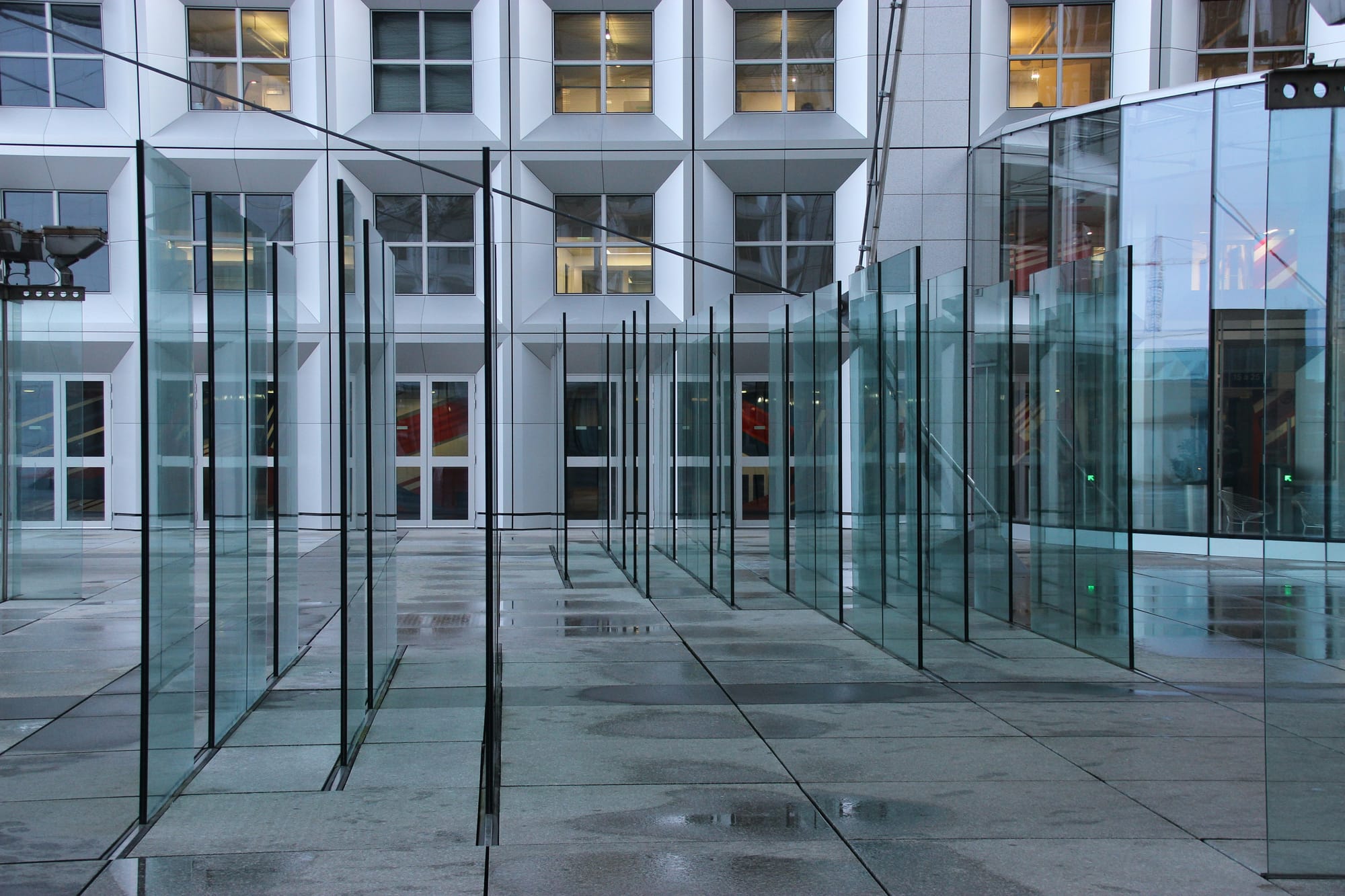 Glass and steel institutional architecture with reflective surfaces creating a cold, imposing corridor